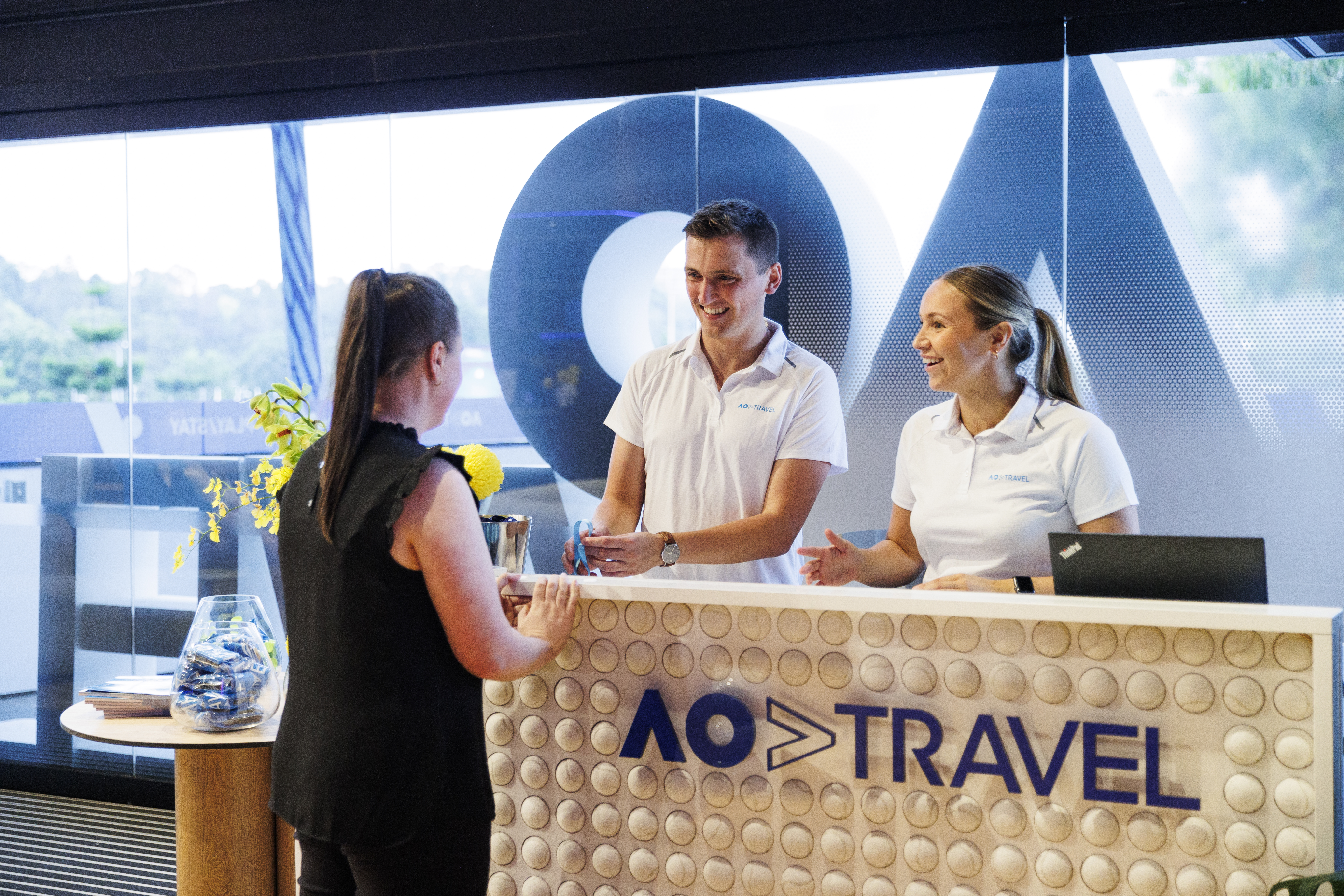 AO Travel staff members interacting with a customer in the AO Travel Lounge.